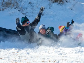 Kevin White, along with his son Bradley and daughter Jessica, bail from their sled as they reach the bottom of the hill while tobogganing Friday in Doidge Park in London. (CRAIG GLOVER, The London Free Press)