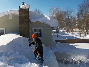 A neighbour shovels snow off his roof in West Seneca, N.Y., after a blizzard. (YouTube)