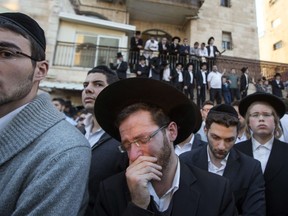 Ultra-Orthodox Jews mourn over the bodies of three of the victims of an attack by two Palestinians on Jewish worshippers killing four Israelis at a synagogue in the Ultra-Orthodox Har Nof neighbourhood in Jerusalem, at the site where the attack took place on November 18, 2014. Two Palestinians armed with a gun and axes burst into a Jerusalem synagogue and killed four Israelis before being shot dead, in the deadliest attack in the city in years. AFP PHOTO/ JACK GUEZ