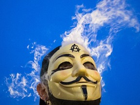 Vapor passes through a Guy Fawkes mask as a man smokes while joining supporters of the Anonymous movement who were taking part in the global "Million Mask March" protests in Union Square, New York November 5, 2014. REUTERS/Elizabeth Shafiroff