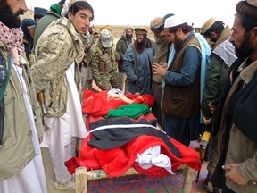 Afghan men gather around the bodies of victims of Sunday's suicide attack at a volleyball match in Yahya Khail district, Paktika province, November 24, 2014. A suicide bomber detonated his explosive vest in a crowd of spectators at a volleyball match in Afghanistan on Sunday, killing 45 people, a provincial official said, as foreign troops withdraw from the country after more than a decade of fighting.  REUTERS/Stringer