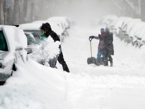 People clear snow from around vehicles during the snowstorm that hit Montreal on Sunday, December 15, 2013. (Joel LemayQMI Agency)