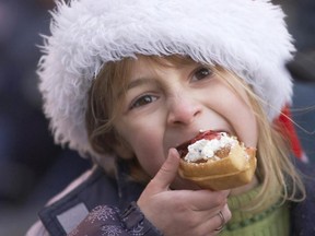A young visitor to Kitchener's Christkindl Market enjoys a yummy waffle. Visitors to the festival can try many traditional foods. (Handout)