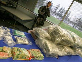 A Halton Region Police officer stands guard Tuesday, November 25, 2014 over 48 kilos of marijuana, 2.5 kilos of cocaine and $155,000 in cash that were seized in raids that ended with the arrest of 15 people in Halton Region. (Dave Thomas/Toronto Sun)
