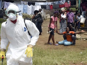 People look on as a woman reacts after her husband is suspected of dying from the Ebola virus, in the Liberian capital Monrovia. By far the most deadly epidemic of Ebola on record has spread into five west African countries since the start of 2014, infecting more than 7,000 people and killing about half of them. 
QMI AGENCY FILE