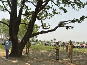 In this photograph taken on May 31, 2014, Indian police officials keep watch at the tree where the bodies of gang rape victims were found hanging in Katra Shahadatgunj in Badaun district, in the northern Indian state of Uttar Pradesh.   AFP PHOTO/Chandan KHANNA/FILES