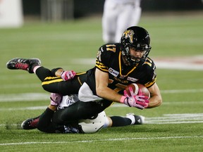 Luke Tasker is tackled in first half football action as the Hamilton Tiger Cats play the Ottawa Redblacks at Tim Hortons Field on October 17, 2014. (Stan Behal/Toronto Sun/QMI Agency)