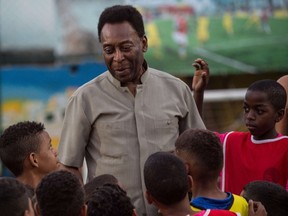Legendary Brazilian former football player Pele speaks with children during the inauguration ceremony of the new technology football pitch installed at Mineira favela in Rio de Janeiro on September 10, 2014. (AFP PHOTO/YASUYOSHI CHIBA)