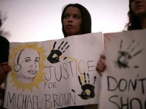 Levonna Cavallo, 18, (L) and Krista Fonseca, 18, hold signs as they listen to speakers during a rally in Los Angeles, California, following Monday's grand jury decision in the shooting of Michael Brown in Ferguson, Missouri, November 26, 2014. REUTERS/Lucy Nicholson