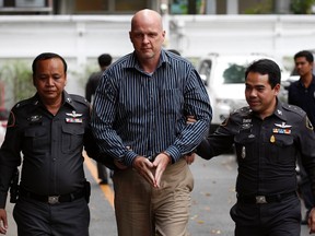 Police officers escort Thomas Andrew Erickson (C), a 47-year-old American, before a news conference at the Central Investigation Bureau in Bangkok November 28, 2014. Police arrested Erickson in Samut Prakan on charges of rape and assault, crimes he allegedly committed in the United States and Thailand, according to local media. The arrest warrants were issued by Denton County Court and Harris County in Texas and by the Criminal Court in Thailand, the report added.  REUTERS/Chaiwat Subprasom