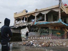 A man looks at the site of a car bomb attack in Baghdad's Shaab neighbourhood on Nov. 25. The bomb killed eight people and wounded 22, police and medics said. (Wissm al-Okili/Reuters)