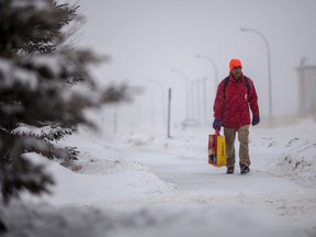 Monty Mehta, walks to work along 49 Avenue in Whitecourt, Alta. in the midst of a major snowfall on Thursday, Nov. 27, 2014. A winter storm warning was issued by Environment Canada stating that up to 75 cm could fall on parts of north-central, western and southwestern Alberta. The storm was brought on by a Pacific weather system, which swept over the Rockies bringing with it lots of snow. In Whitecourt, some school buses were cancelled and the Santa Claus parade, scheduled for Nov. 28 had to be rescheduled for Dec. 12, 2014. ADAM DIETRICH/WHITECOURT STAR/QMI AGENCY