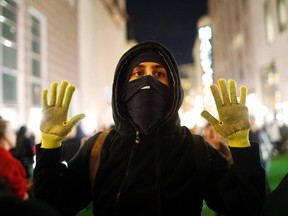 A masked protester raises his hands during a demonstration against a grand jury's decision in the Ferguson, Missouri shooting of Michael Brown, near Union Square in San Francisco, California November 28, 2014. (REUTERS/Stephen Lam)