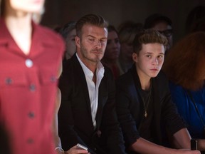 Soccer player David Beckham and his son Brooklyn Beckham watch a model present a creation during the Victoria Beckham Spring/Summer 2015 collection during New York Fashion Week in the Manhattan borough of New York September 7, 2014.    REUTERS/Carlo Allegri