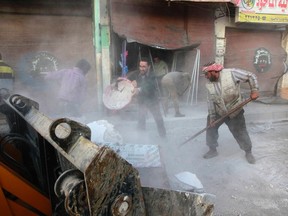 Residents remove debris from collapsed buildings after what activists said were four air strikes by forces loyal to Syria's president Bashar Al-Assad in Raqqa November 28, 2014. REUTERS/Nour Fourat