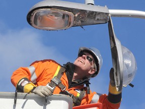 Jim Keech, president and CEO of Utilities Kingston, prepares to remove an old light fixture on a pole on Willingdon Avenue, prior to replacing it with the final new LED light to be installed in the city in an 18-month project. (Michael Lea/The Whig-Standard)