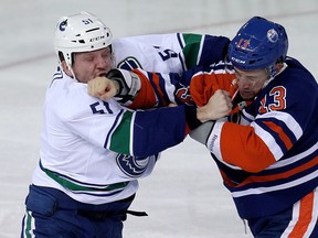 The Edmonton Oilers' Steven Pinizzotto (13) drops the gloves with Vancouver Canucks' Derek Dorsett (51) during the first period at Rexall Place, in Edmonton Alta., on Wednesday Nov. 19, 2014. David Bloom/Edmonton Sun/QMI Agency