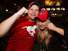 Aron Turgeon, left, and Kortnaey Cunningham, both new to Edmonton from Calgary, cheer on the Calgary Stampeders as they watch the  Grey Cup  at Schanks in Edmonton. (CODIE MCLACHLAN/Edmonton Sun)