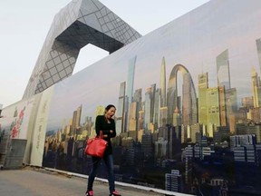 A woman walkS past a poster showing Beijing's central business district next to the China Central Television (CCTV) building in Beijing, October 21, 2014.   REUTERS/Jason Lee