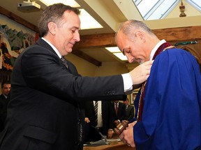 Outgoing mayor Neil Ellis places the chain of office on the shoulders of his successor, Taso Christopher, at city hall Monday, December 1, 2014 in Belleville, Ont. The pair spent the last two terms on council together. Luke Hendry/The Intelligencer/QMI Agency