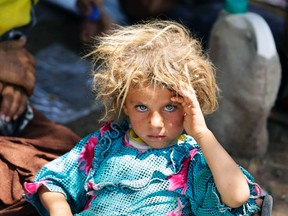 A girl from the minority Yazidi sect, fleeing the violence in the Iraqi town of Sinjar, rests at the Iraqi-Syrian border crossing in Fishkhabour, Dohuk province, Aug. 13, 2014. (YOUSSEF BOUDLAL/Reuters)