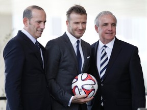 Don Garber (L), MLS commissioner, Miami-Dade County Mayor Carlos Gimenez (R) and David Beckham pose for a photo after a news conference in Miami, Florida February, 5, 2014. Former England soccer captain Beckham announced that he was exercising his option to become the owner of a Major League Soccer team in Miami.    REUTERS/Andrew Innerarity