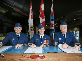 Former mayor of Quinte West John Williams, right, is appointed as the new Honorary Colonel of 8 Wing/CFB Trenton, Ont. at the National Air Force Museum of Canada in Trenton, Ont. Wednesday, Dec. 3, 2014. Outgoing Honorary Colonel Armin Quickert, left, and Commanding Officer of 8 Wing Col. Dave Lowthian sign official documents, along with Williams.  - JEROME LESSARD/THE INTELLIGENCER/QMI AGENCY