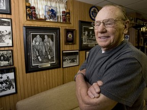 Johnny Bower looks over some old hockey photos in his basement. (QMI Agency file photo)
