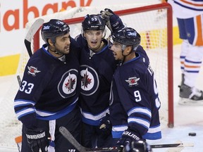 Dustin Byfuglien #33 of the Winnipeg Jets celebrates his goal with teammates Mark Scheifele #55 and Evander Kane #9 in third period action in an NHL game against the Edmonton Oilers at the MTS Centre on December 3, 2014 in Winnipeg, Manitoba, Canada.