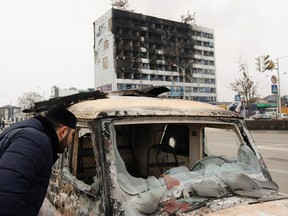 A man looks into a burnt-out car near the Press House building, a local media agency, in the Chechen capital Grozny, December 4, 2014. (REUTERS/Stringer)