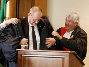 Hastings County CAO Jim Pine, left, with Justice Robert Scott, right, helps Warden Rick Phillips into his robes during the inaugural session of Hastings County council in Belleville, Ont. - EMILY MOUNTNEY-LESSARD/THE INTELLIGENCER/QMI AGENCY