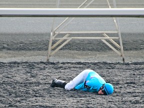 Jockey Jesse Campbell lies on the Woodbine track after falling off his mount Sweet Corinna at the start of the second race on Saturday. (Mike Campbell/photo)