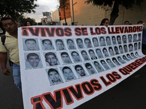 Protesters hold up a banner with pictures of missing students from the Ayotzinapa Teacher Training College Raul Isidro Burgos, during a march supporting them in Mexico City December 6, 2014. (REUTERS/Henry Romero)