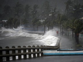 Residents walk past high waves brought about by strong winds as it pound the seawall, hours before Typhoon Hagupit passes near the city of Legazpi on December 7, 2014.  Typhoon Hagupit tore apart homes and sent waves crashing through coastal communities across the eastern Philippines, creating more misery for millions following a barrage of deadly disasters. (TED ALJIBE/AFP PHOTO)
