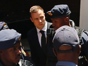 South African Olympic and Paralympic sprinter Oscar Pistorius (C) is escorted to a police van after his sentencing at the North Gauteng High Court in Pretoria October 21, 2014. Pistorius was sentenced to five years in prison on Tuesday for killing his girlfriend Reeva Steenkamp, ending a trial that has gripped South Africa and the world. REUTERS/Siphiwe Sibeko