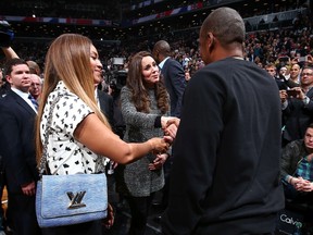 Britain's Catherine (C), Duchess of Cambridge, is greeted by recording artists Beyonce (L) and Jay-Z as they attend the NBA basketball game between the Cleveland Cavaliers and the Brooklyn Nets in New York in this December 8, 2014 handout photo by the NBA. REUTERS/NBAE/Handout via Reuters