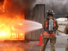 A Toronto firefighter extinguishes a blaze started by an improperly decorated holiday room during safety demonstration at the Toronto Fire Academy on Tuesday, December 9, 2014. (Jack Boland/Toronto Sun)