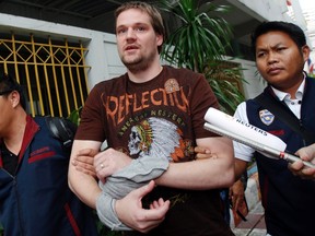 Hans Fredrik Lennart Neij (C), a co-founder of the Swedish file-sharing website, The Pirate Bay, is escorted by Thai police officers as he arrives at the Immigration Detention Center in Bangkok Nov. 5, 2014. REUTERS/CHAIWAT SUBPRASOM