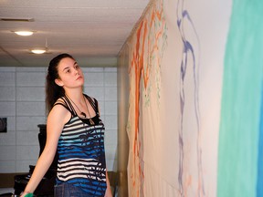 Emma Fitzgerald pauses to contemplate the mural she painted along with fellow student Jeremy Bramer and art teacher Karen Paton during the community conversation on learning at the Pincher Creek community hall on Nov. 25, 2014. John Stoesser photos/ QMI Agency