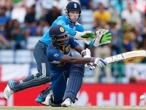 Sri Lanka’s captain Angelo Mathews (bottom) plays a shot as England’s wicketkeeper Jos Buttler tries to stop the ball during their fifth one day international match in Pallekele, Sri Lanka, yesterday. The match stopped because of rain and will resume Thursday. (REUTERS)