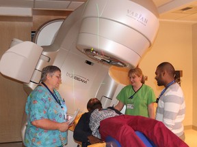 Radiation therapist Daniel Laryea demonstrates how a patient would undergo a radiation treatment with a new piece of radiation therapy equipment at the Cancer Centre of Southeastern Ontario in Kingston. With him are fellow radiation therapists Annette Cornell, left, Heather Watters and Viraj Rudra. (Michael Lea/The Whig-Standard)