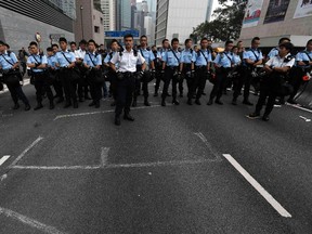 Police stand as workers clear an area blocked by pro-democracy protesters near the government headquarters building at the financial Central district in Hong Kong, December 11, 2014.  REUTERS/Athit Perawongmetha