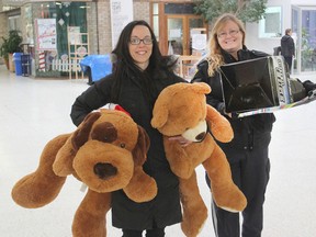 Brandi Timpson, left, and Angie Hogle carry the last of the toys donated under the city's Toys for Tickets program into the Frontenac Mall to the toy drive distribution centre. (Michael Lea/The Whig-Standard)