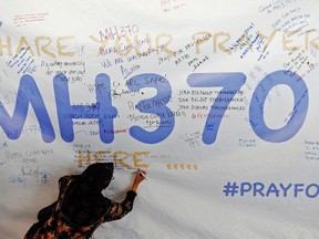 A woman writes a message of support and hope for the passengers of the missing Malaysia Airlines MH370 on a banner at Kuala Lumpur International Airport on March 12, 2014. (REUTERS/Damir Sagolj)