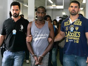 Sailson Jose das Gracas, 26, is escorted by policemen at a police station in Nova Iguacu near Rio de Janeiro December 11, 2014. Gracas, who was arrested on Wednesday, told reporters at a police station in the state of Rio that he killed for pleasure and the accompanying adrenaline rush. He said he also operated as a killer for hire. He said his preferred victims were white females, whom he strangled. Among the 42 victims, 39 are thought to be women.  REUTERS/Fabio Golcalves/Agencia O Dia