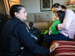 Sgt. Elli McEvoy, left, delivers presents to Maria and her 11-month-old son, Jacob Garcia, during Edmonton Police Service's Blue Santa program, which sees police officers delivering gifts to families on behalf of Santa's Anonymous in Edmonton, Alta., on Friday, Dec. 12, 2014. Codie McLachlan/Edmonton Sun