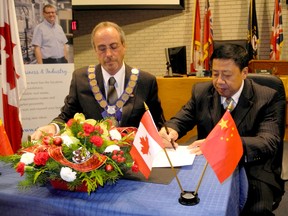 Zhang Xiaohua, vice-chairman of the Changchun Municipal Committee, signs an agreement in council chambers Friday with Mayor Randy Hope to promote economic, educational and cultural exchanges between the two communities. (Trevor Terfloth, The Daily News)