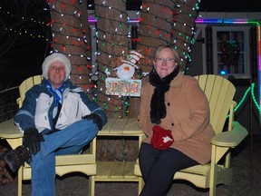 Dennis Taylor, left, and Raymie Jewell sit in the backyard of their Port Stanley home, which is lit up with about 73,000 Christmas lights. The display is an annual venture for the couple, raising more than $18,700 for the Make-A-Wish Foundation and about 7,000 pounds of food for the Port Stanley food bank since 2010. (Ben Forrest, Times-Journal)