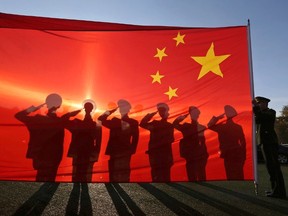 Retired paramilitary policemen, who conduct the daily national flag raising and lowering ceremony on Tiananmen Square, salute to a Chinese national flag during a farewell ceremony in Beijing, November 24, 2014. (REUTERS/Stringer)