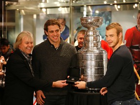 Hockey Hall of Fame curator Phil Pritchard (left) and Los Angeles Kings players Anze Kopitar (centre) and captain Dustin Brown (right) pose with a 2014 Stanley Cup ring which the Kings donated to the Hockey Hall of Fame's collection in Toronto on  Dec. 13, 2014. (MICHAEL PEAKE/Toronto Sun)